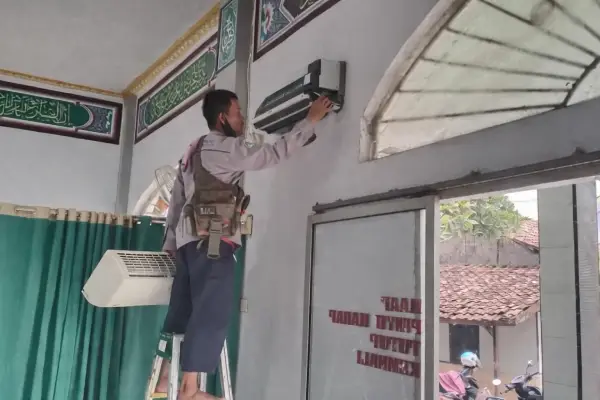 seorang pengurus masjid terlihat tengah mengecek kondisi ac masjid.